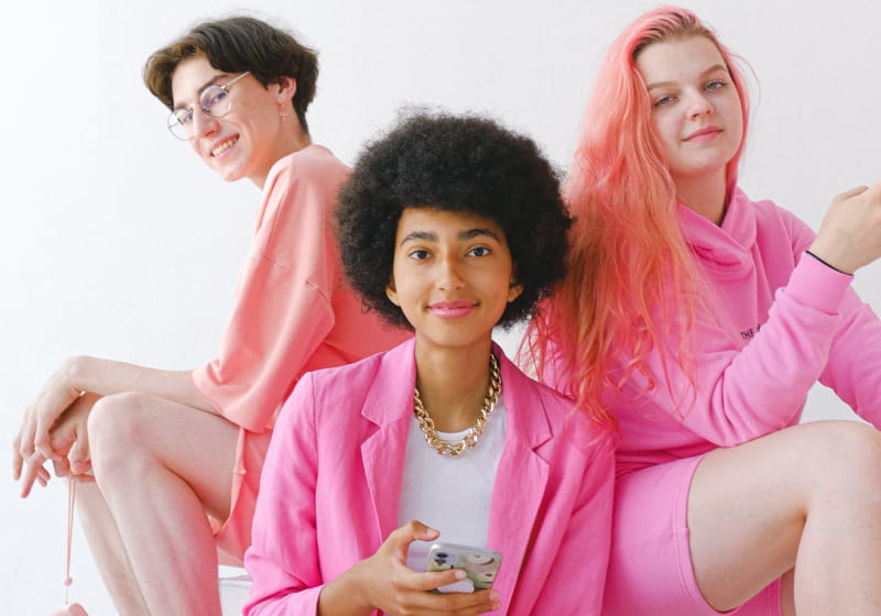 três jovens sentados com roupas cor de rosa