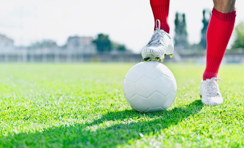 Sapatos de jogador de futebol de bola de futebol e pé no campo