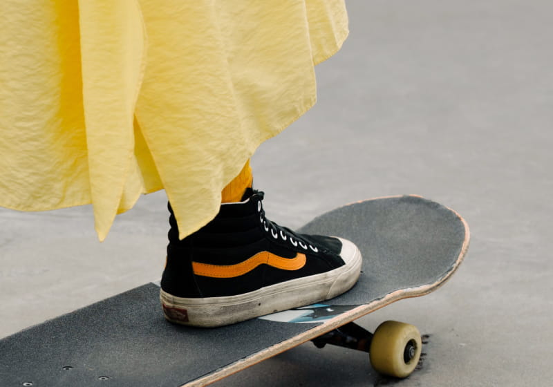 menina com pé nos skate com vestido amarelo e tênis 