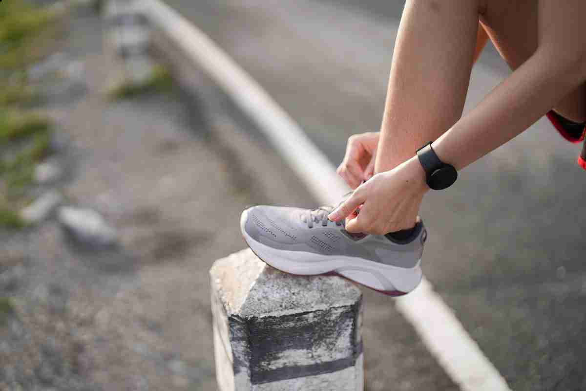 pessoa com pé encima de um muro amarrando cadarço para iniciar a corrida