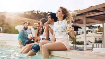 um grupo de amigos sentados na beira da piscina em uma festa na piscina em um dia de verão