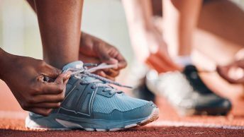 pessoas que vão correr em uma maratona arrumando o tênis em uma pista própria para corrida