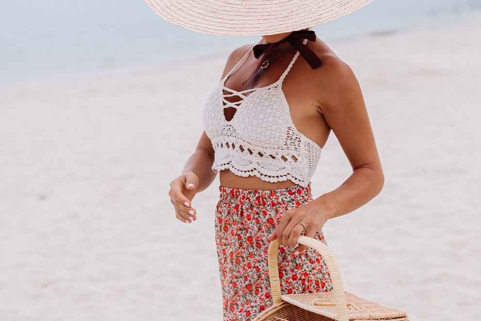 uma mulher usando uma saia midi estampada e um top de croche em uma praia