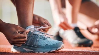 Atleta amarrando tênis em pista de corrida