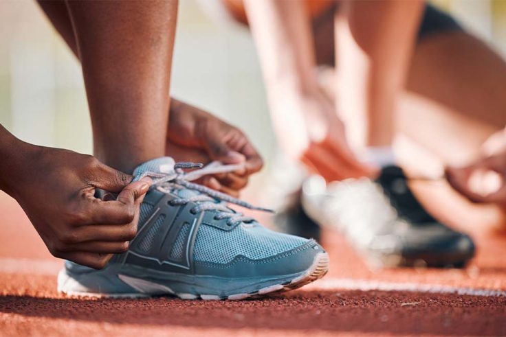 Atleta amarrando tênis em pista de corrida