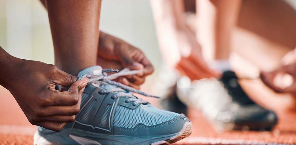 Atleta amarrando tênis em pista de corrida
