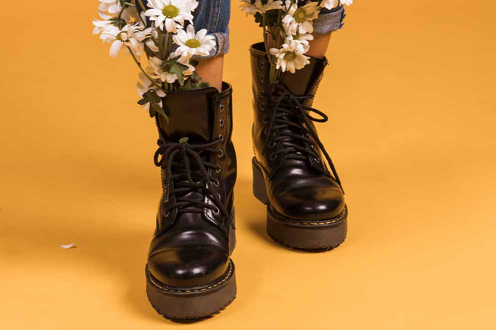 Botas pretas com flores brancas em fundo amarelo