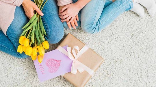 Mãe e filha com flores e presente no chão