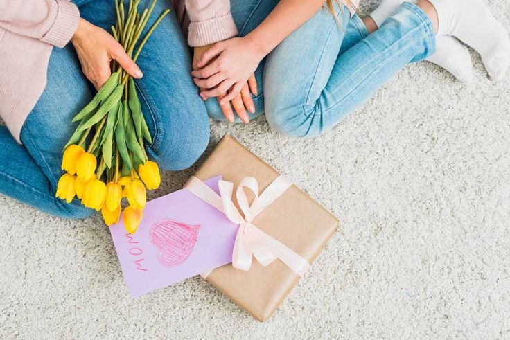 Mãe e filha com flores e presente no chão
