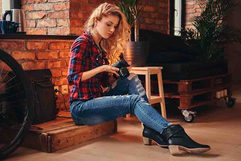 Mulher sentada com câmera em ambiente aconchegante