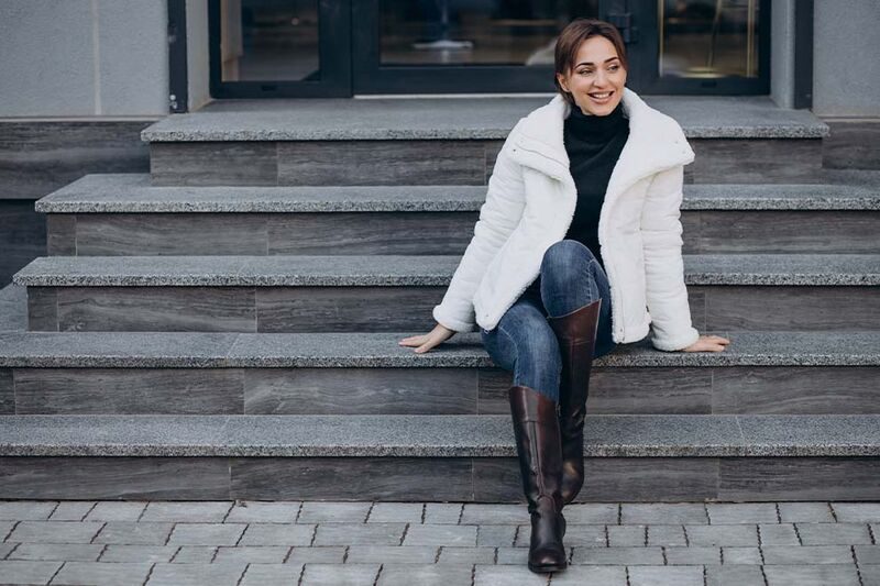 Mulher sorridente usando casaco branco sentada na escada