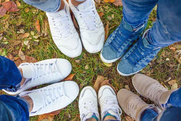 Várias pessoas com diferentes tênis em um ambiente natural.