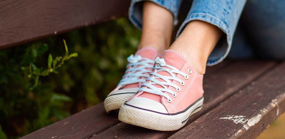 Tênis rosa sobre banco de madeira