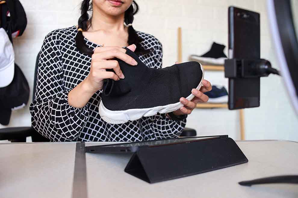 Pessoa segurando um tênis preto em estúdio.