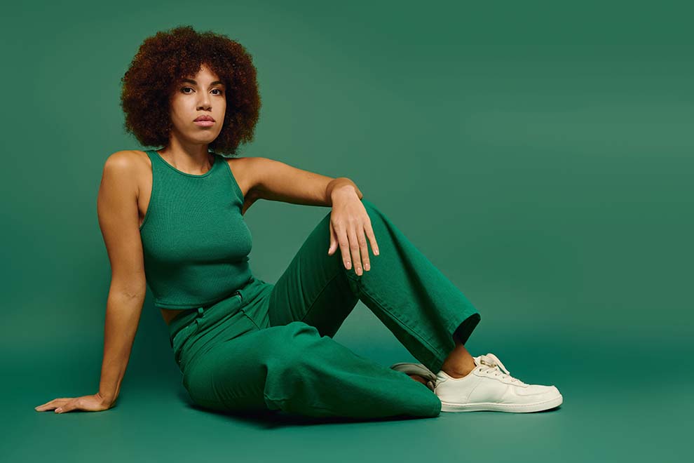 verde jade Mulher com cabelo cacheado vestindo verde em fundo verde.