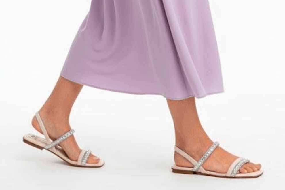 Sandálias adornadas caminhando sobre vestido lilás