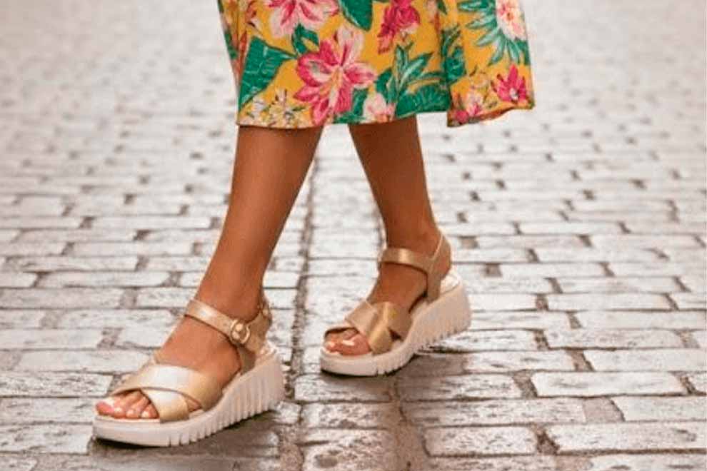 Sandália dourada com salto alto em calçada de pedra