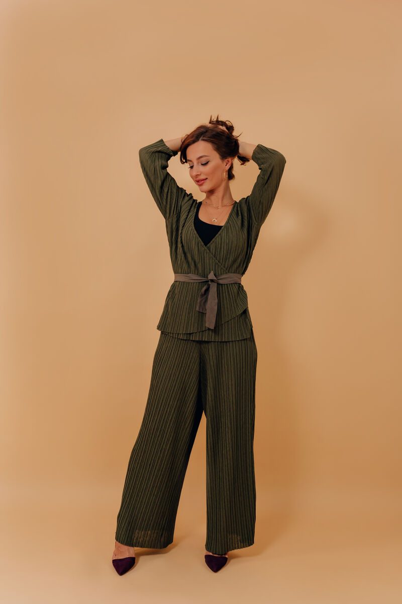 Mulher posando com roupa verde em fundo neutro