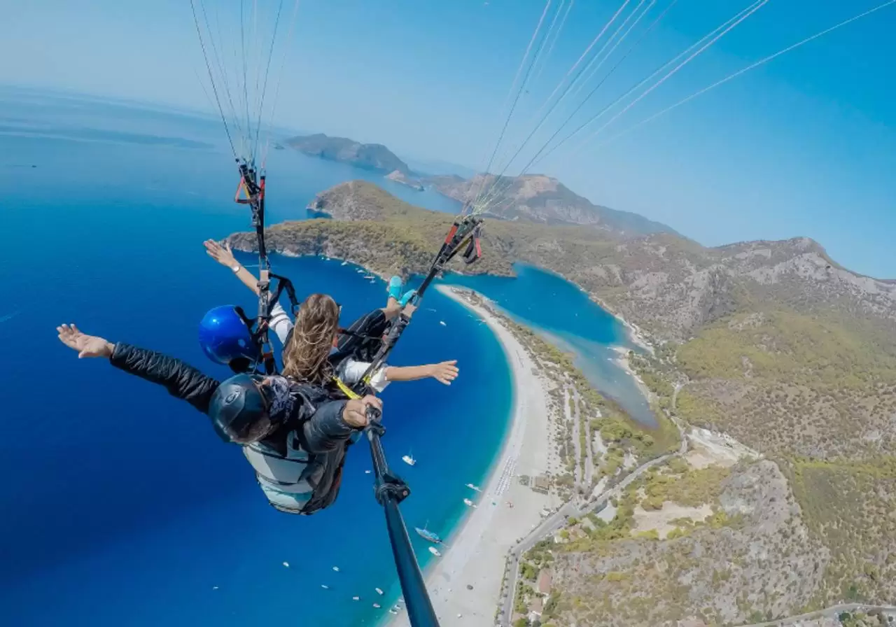 vista de cima de casal fazendo salto de paraquedas na praia