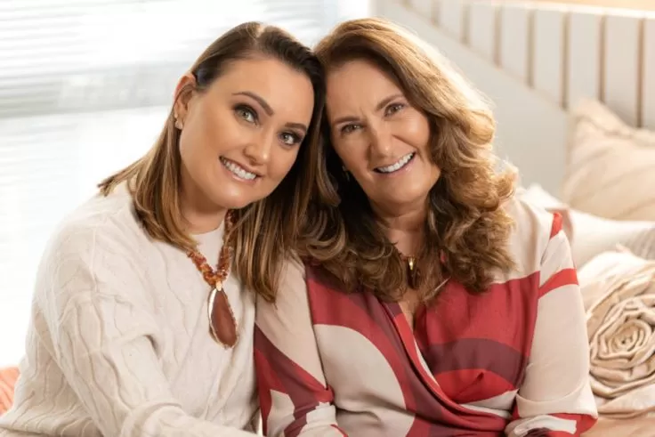 mãe e filha olhando para câmera sentadas juntas