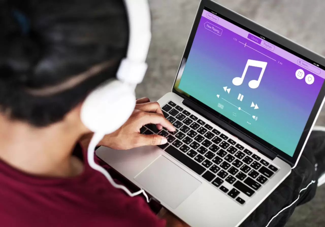 vista de traz de homem vendo musicas online em notebook com fone de ouvido