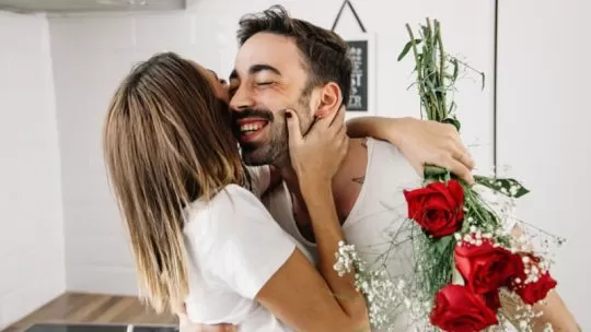 mulher abraçando seu namorando pelas flores de presente