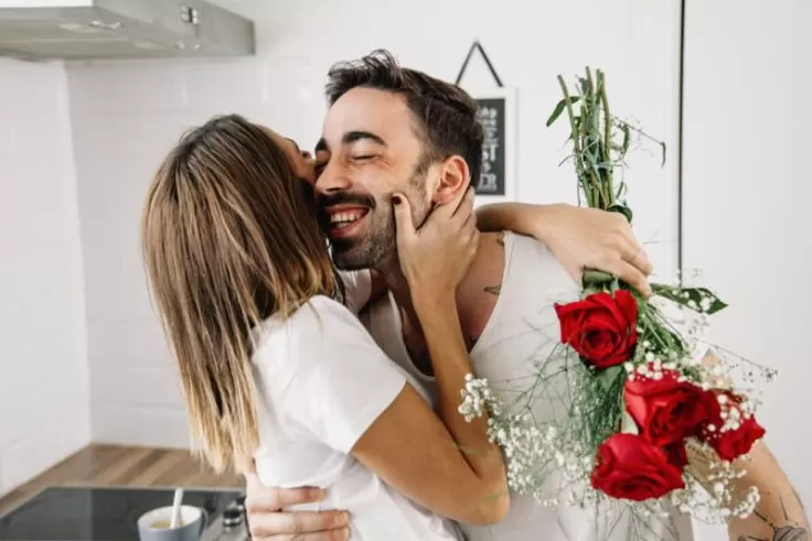 mulher abraçando seu namorando pelas flores de presente