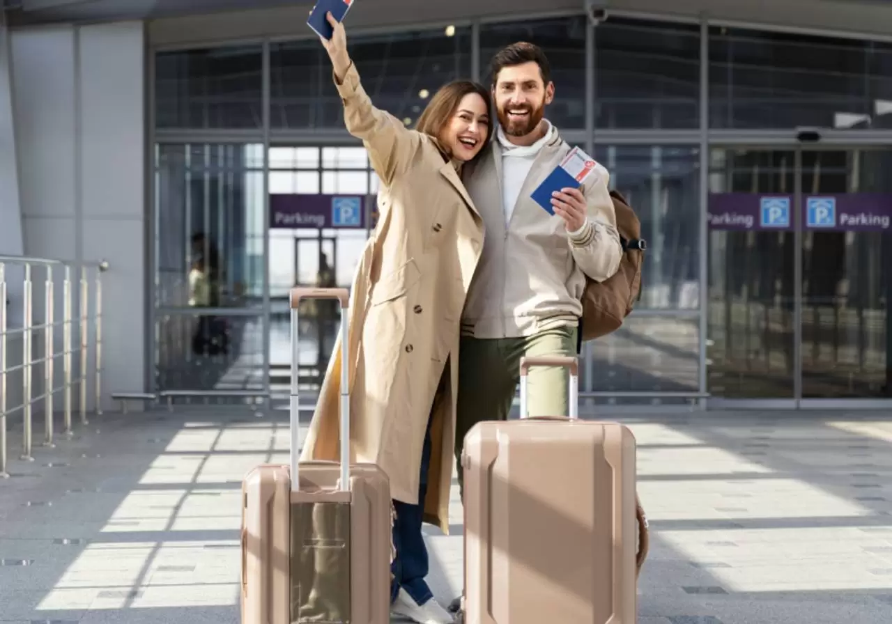 casal feliz em frente ao aeroporto com malas e passaporte 