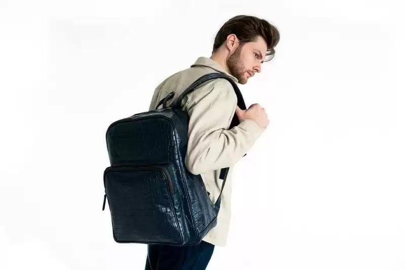 Imagem de um modelo de costas, usando uma bolsa de couro azul casual em um fundo branco de estúdio 