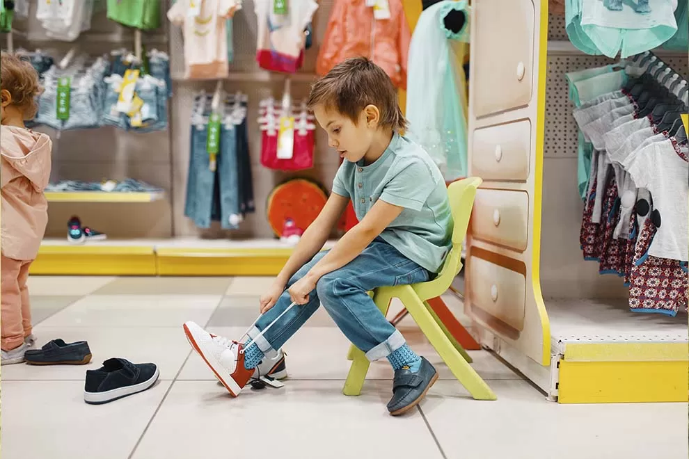 Menino provando um tênis em uma loja de roupas para criança 