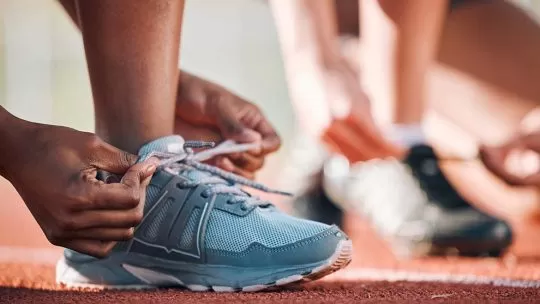pessoas que vão correr em uma maratona arrumando o tênis em uma pista própria para corrida