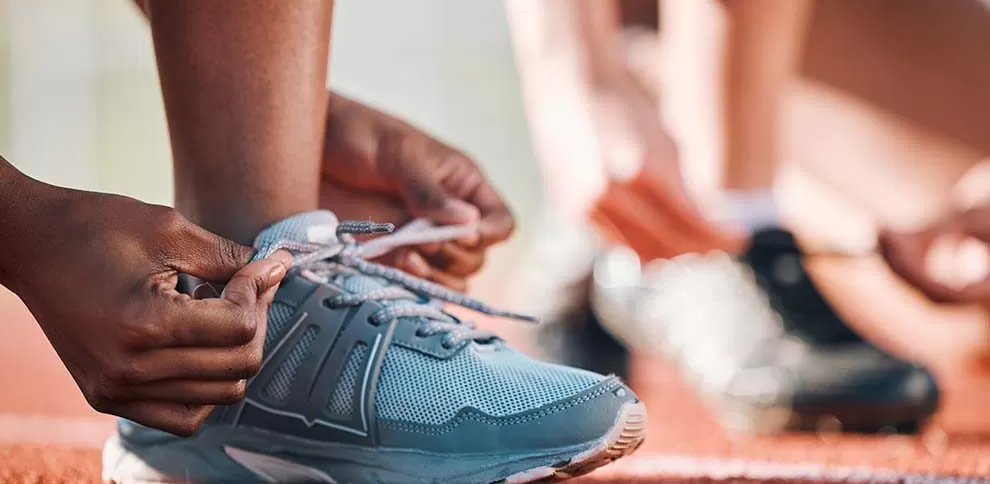 pessoas que vão correr em uma maratona arrumando o tênis em uma pista própria para corrida