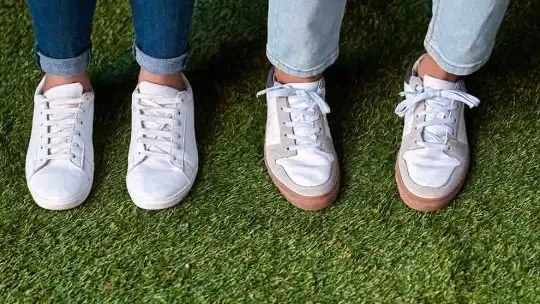duas pessoas usando tênis branco em um gramado