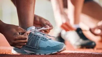 Atleta amarrando tênis em pista de corrida