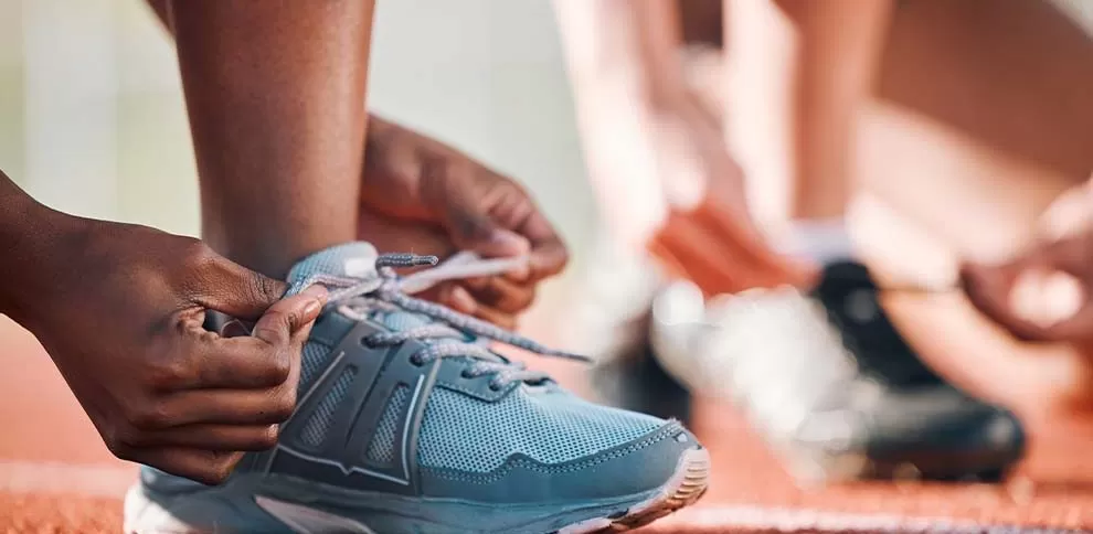 Atleta amarrando tênis em pista de corrida