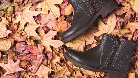 Botas de couro sobre folhas secas de outono.