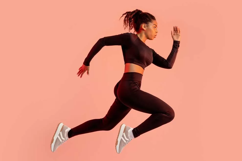 Mulher correndo em fundo rosa vibrante.