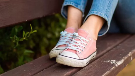 Tênis rosa sobre banco de madeira