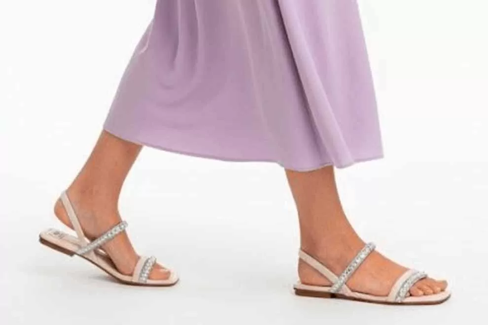 Sandálias adornadas caminhando sobre vestido lilás