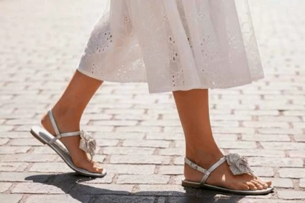 Sandálias prateadas com detalhes, caminhando em calçada