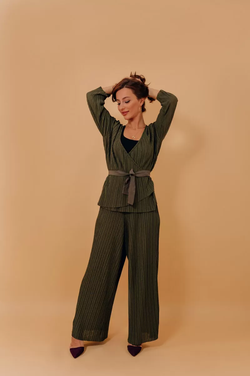 Mulher posando com roupa verde em fundo neutro