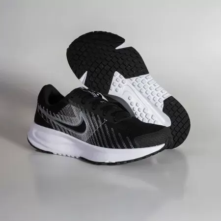 Tênis de corrida Nike preto e branco sobre fundo neutro